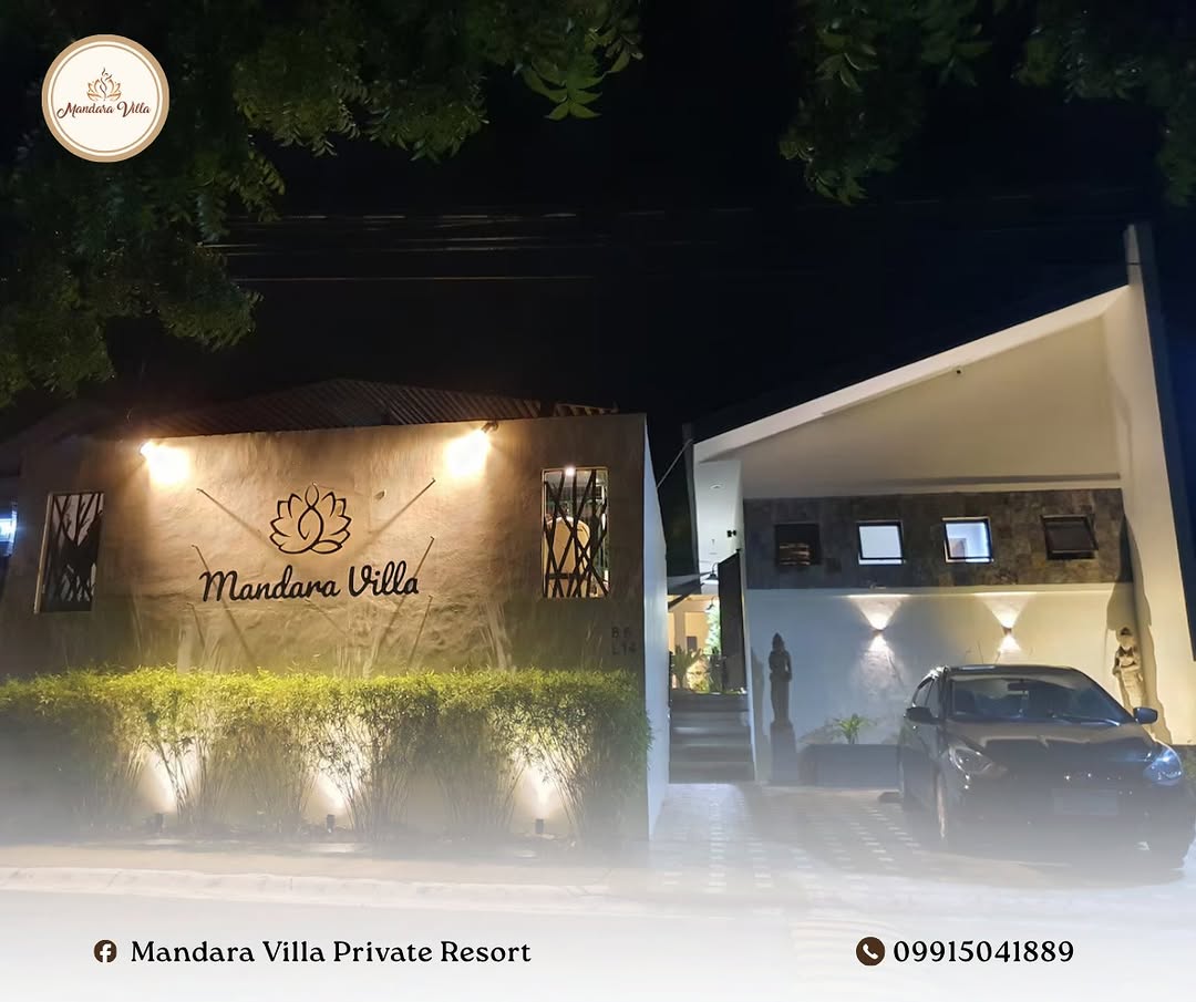 Night entrance of Mandara Villa — illuminated lotus sign and gated driveway